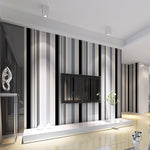 Modern living room with a striped wall design and a television.